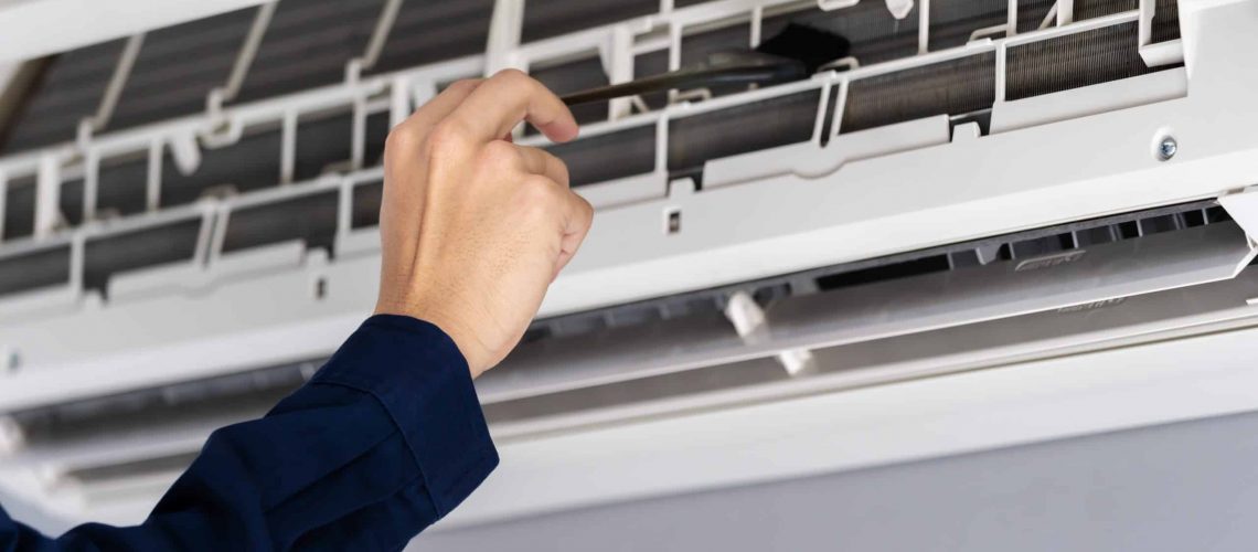 close up technician service using brush to cleaning the air conditioner indoors